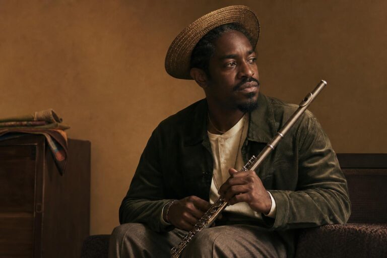 André 3000 holding a flute in a studio portrait